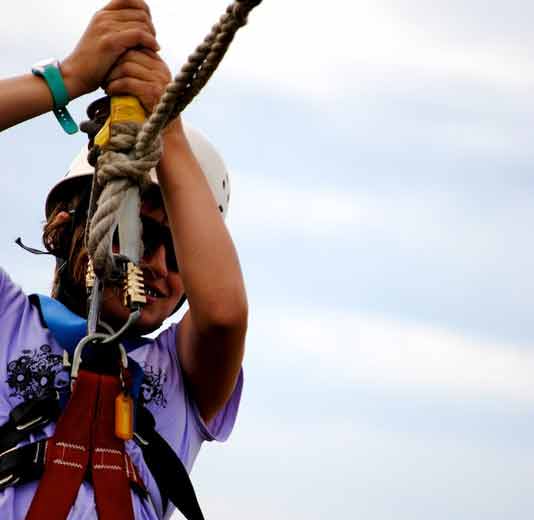 Kid on a hanging rope wearing helment and harness